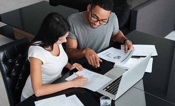 Happy loving young couple using laptop and analyzing finances